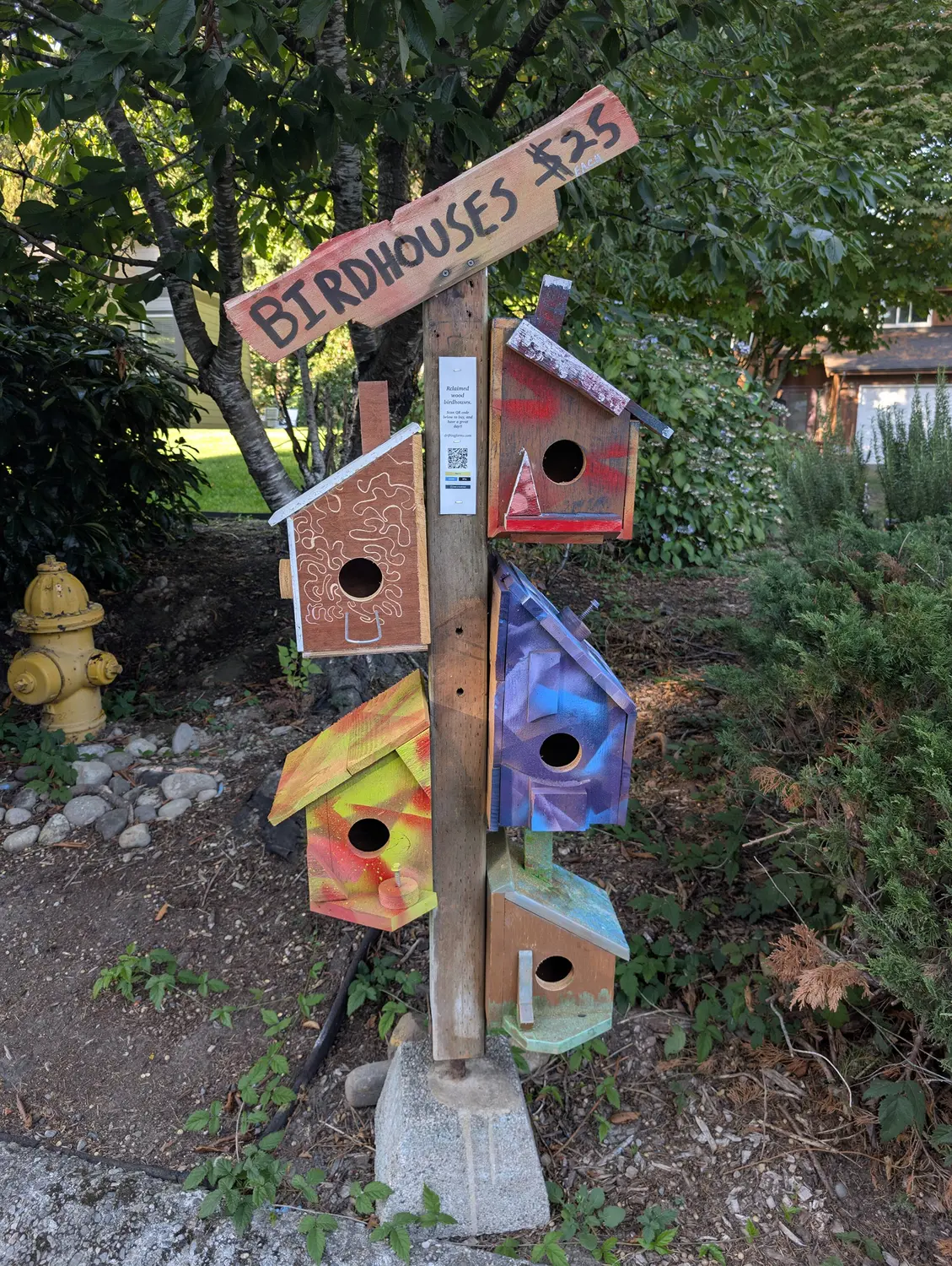 A hand-built wooden stand displaying five colorful birdhouses